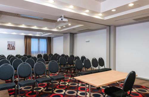 a conference room with chairs and tables and a screen at Leonardo Vienna Westbahnhof in Vienna