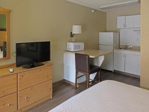 a hotel room with a bed and a desk with a television at Suburban Studios Raleigh - Crabtree Valley in Raleigh
