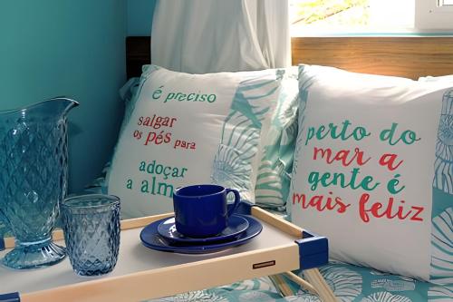 a bed with a table with a coffee cup and pillows at Stúdio inteiro climatizado próximo a praia - ambiente familiar in Itapema