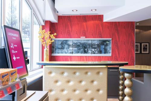 a bar in a restaurant with a red wall at Leonardo Vienna Westbahnhof in Vienna