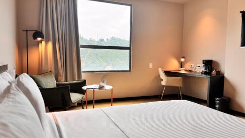 a hotel room with a bed and a desk and a window at Tequendama Hotel Medellín - Estadio in Medellín