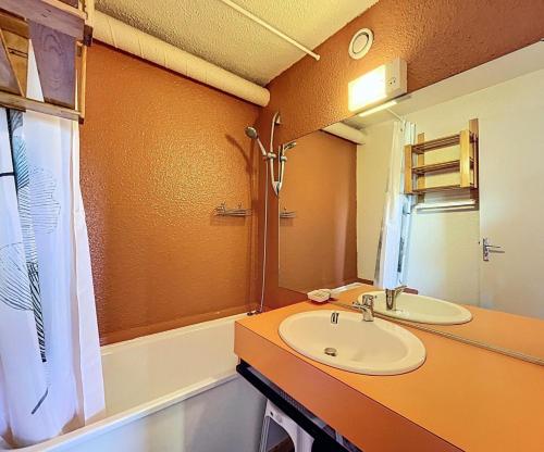 Un baño con lavabo, espejo y bañera. en Résidence Pegase - APPARTEMENT 2 PIECES 5 PERSONNES MAE-9724, en Le Corbier