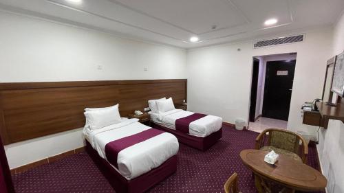 a hotel room with two beds and a table at فندق الأصالة البكية توصيل مجاني الى الحرم - ALAsalah ALBakkiya Hotel Free Shuttel Service in Al Masfalah