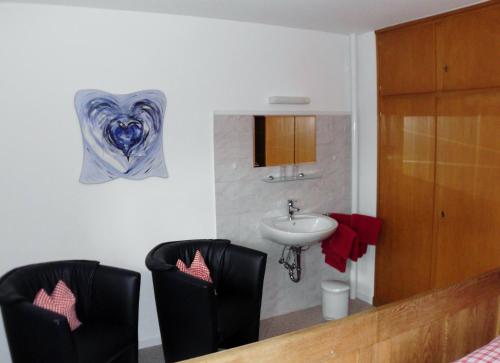 ein Badezimmer mit zwei schwarzen Stühlen und einem Waschbecken in der Unterkunft Ferienhaus Suedhang in Winterberg