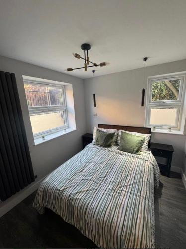 1 dormitorio con 1 cama con 2 almohadas y 2 ventanas en Beautiful Central Croydon Rooms - 5 mins to train, en South Norwood