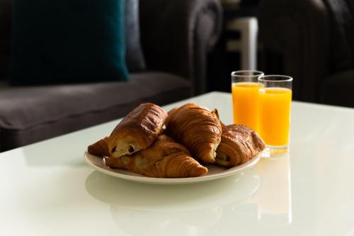 a plate of croissants on a table with orange juice at Saint Lazare à portée de main in Argenteuil