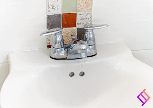 ein Waschbecken mit zwei Chromhähnen darauf in der Unterkunft Apto moderno al norte cerca al Río Guatapurí in La Elvira