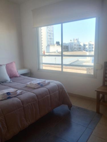 a bedroom with a bed and a large window at Dpto Zapiola - 2 Ambientes 3er piso por escalera in Bahía Blanca