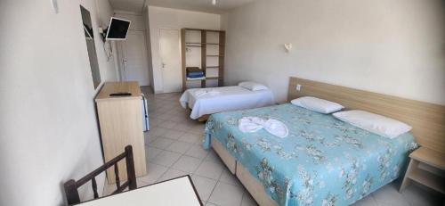 a hotel room with two beds and a television at Hotel Kolman in Capão da Canoa