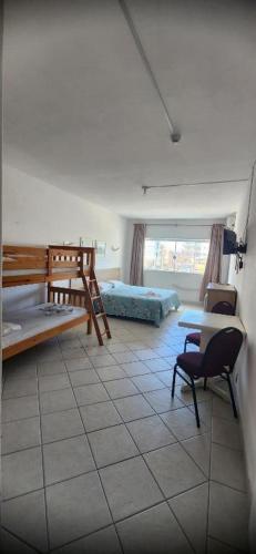 a room with a bedroom with a bed and a desk at Hotel Kolman in Capão da Canoa