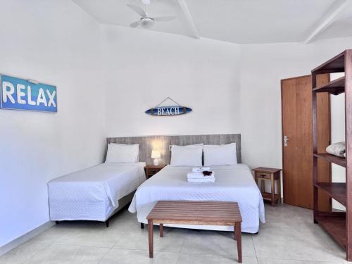 a hotel room with two beds and a table at Bella Buzios Apartamentos in Búzios