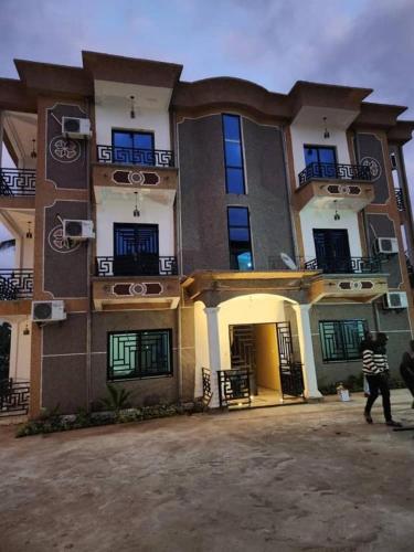 a man walking in front of a large building at MiniGolf, MeteoMode & B2B RESIDENCE Ekoumdoum - DAHARA APPARTS in Yaoundé