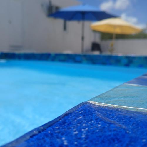 a pool with an umbrella and a swimming pool at Blue Ocean Apartment in Noord