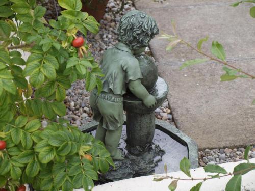 a statue of a little boy sitting in a bird bath at Achnabobane Farmhouse in Spean Bridge
