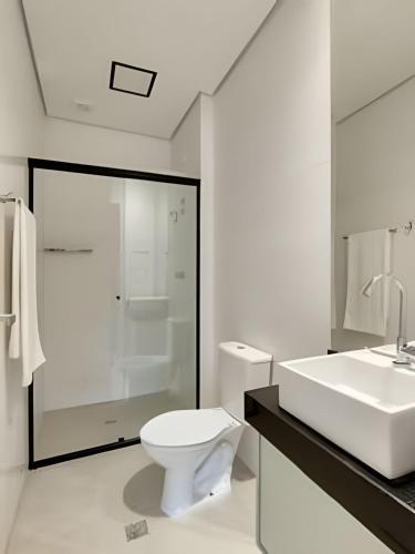 a white bathroom with a toilet and a sink at Studio Luggo Pampulha in Belo Horizonte