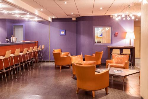 a restaurant with purple walls and chairs and a bar at Hotel des Congrès in Villeurbanne