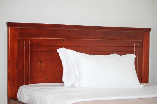 a bed with a wooden headboard and white pillows at Serene villas in Kitala