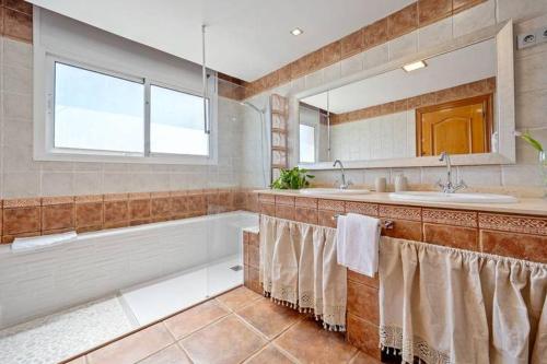 Un baño con bañera, lavabo y espejo. en Private Pool Sea Views Bellvei Villa Barcelona, en Calafell