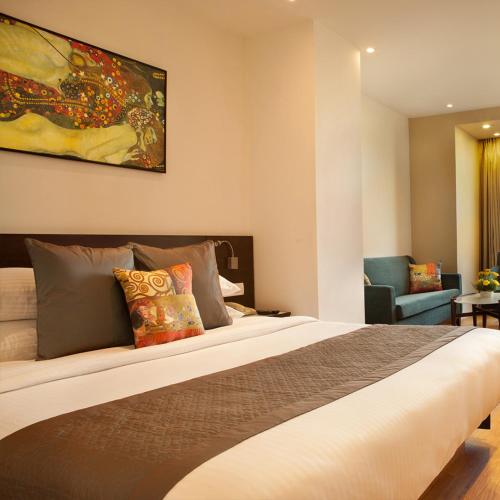a hotel room with a large bed and a chair at Hotel Nysha Delhi in New Delhi