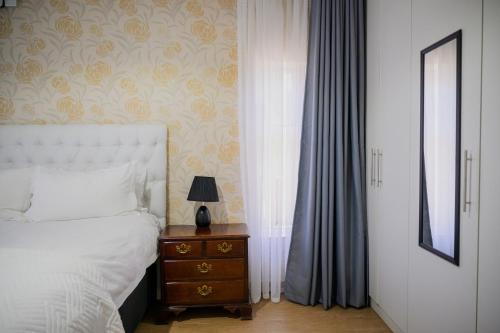 a bedroom with a bed and a table with a lamp at Villa Stone Apartments in Lusaka