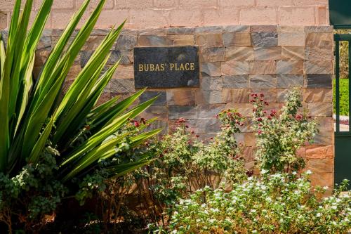 a sign for the bushes place in a garden at Villa Stone Apartments in Lusaka