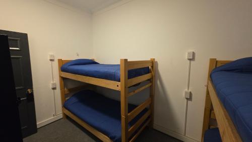 two bunk beds in a room with blue sheets at Oceana Suites Chile Hostel in Santiago