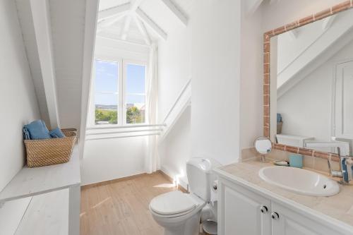 Un baño blanco con lavabo e inodoro. en GOLDEN SUN, en Orient Bay