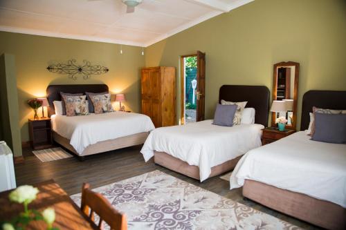 a bedroom with two beds and a table at Franka Guesthouse in Rustenburg