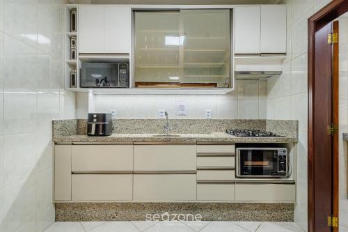 a kitchen with white cabinets and a counter top at Apto c varanda e churrasq em cond beira mar UAR301 in Itapema
