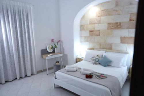 Un dormitorio con una cama blanca y una pared de ladrillo. en CASA VACANZE VIA CASALE, en Nardò