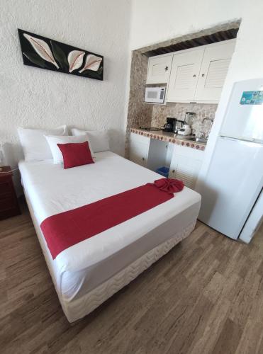 a bedroom with a large white bed and a kitchen at Cancun plaza frente al mar in Cancún