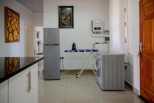 a kitchen with a refrigerator and a washing machine at Villa Stone Apartments in Lusaka