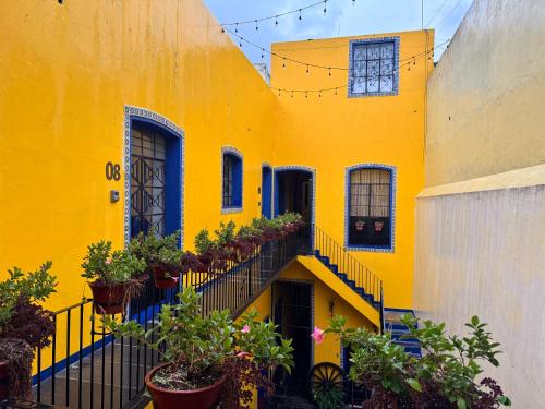 a yellow building with stairs and potted plants at Hostal puebla in San Baltasar