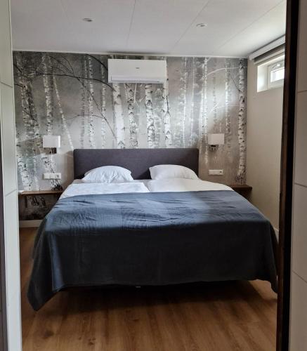 a bedroom with a bed and a wall with trees at Hofstay Twente in Goor