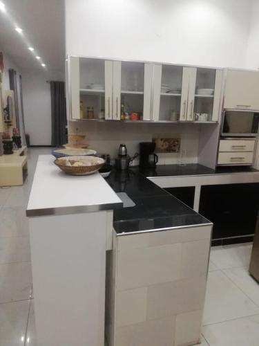 a kitchen with white cabinets and a black counter top at Villa Ngaparou Petite-Côte 2 chambres salon in Ngaparou