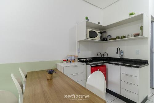 a kitchen with white cabinets and a wooden table at Lindos Lofts no Centro de Floripa - FLT in Florianópolis