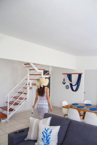 a woman in a hat walking through a living room at Kuxaan Cielo Terraza privada y comodidad a pocos minutos de la playa in Playa del Carmen