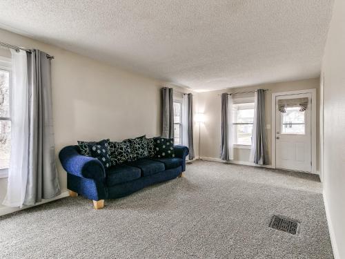 a living room with a blue couch and windows at Cozy House Near Iowa State Fairgrounds! in Des Moines