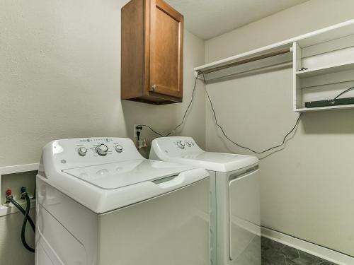 a white washer and dryer in a small bathroom at Cozy House Near Iowa State Fairgrounds! in Des Moines
