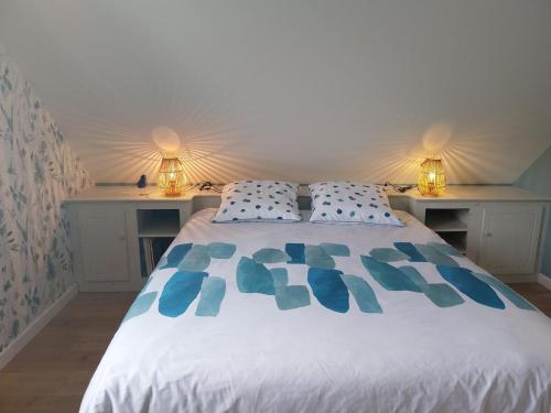 a bedroom with a white bed with blue pillows at L'Aintemporel - Gîte calme 4 personnes in Pont-du-Navoy