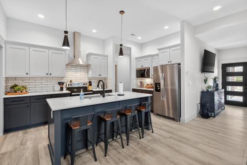 a kitchen with white cabinets and a blue island with bar stools at Plush & Roomy - Perfect for All Ages near KU & KC Duplex in Lawrence