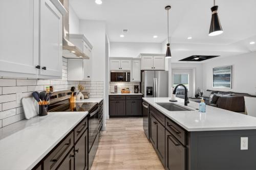 a large kitchen with white cabinets and a sink at Plush & Roomy - Perfect for All Ages near KU & KC Duplex in Lawrence
