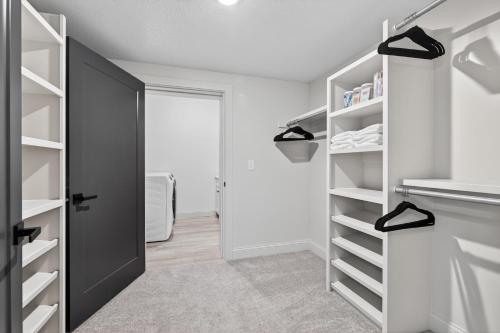 a closet with white shelves and a black door at Plush & Roomy - Perfect for All Ages near KU & KC Duplex in Lawrence