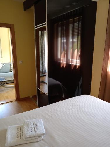 a bedroom with a white bed and a mirror at Apartmani Pezerović in Soko Banja