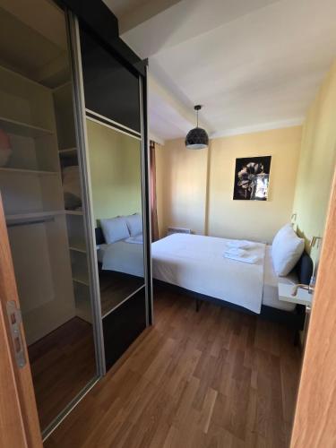 a bedroom with a white bed and a mirror at Apartmani Pezerović in Soko Banja