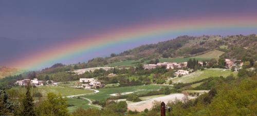a rainbow in the sky over a valley with houses at Gîte du Four à Chaux in Quillan