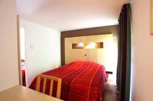 a bedroom with a bed with a red blanket at Hôtel la Scala in Pithiviers