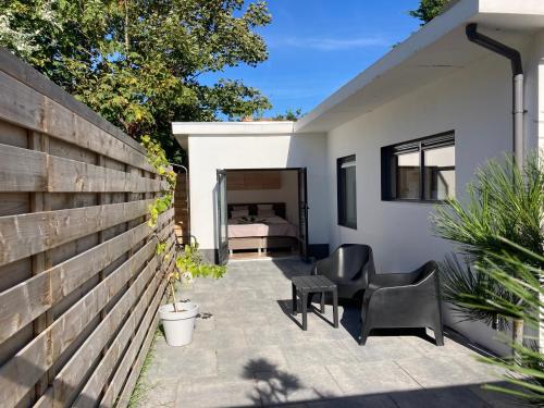 a patio with two chairs and a bed in a bedroom at Noordster Beachhouse, Noordwijk aan Zee in Noordwijk