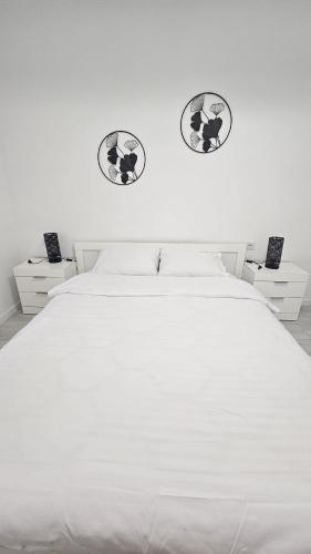 a bedroom with a white bed with two pictures on the wall at Apartament Alb&Negru in Sebeş