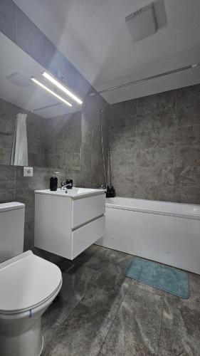 a bathroom with a toilet and a sink and a tub at Apartament Alb&Negru in Sebeş